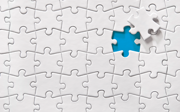 A jigsaw puzzle with white pieces. One piece has been removed showing a blue background