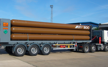 A BOC truck delivering helium gas in bulk tubes on a trailer