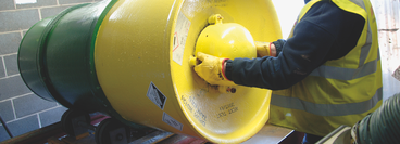 An employee safely rolling a drum of sulphur dioxide