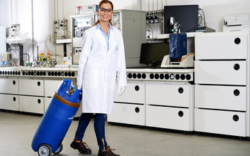A female scientist in a laboratory pulling a GENIE gas cylinder on wheels