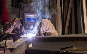 Close-up of a welder, dressed in protective equipment, welding
